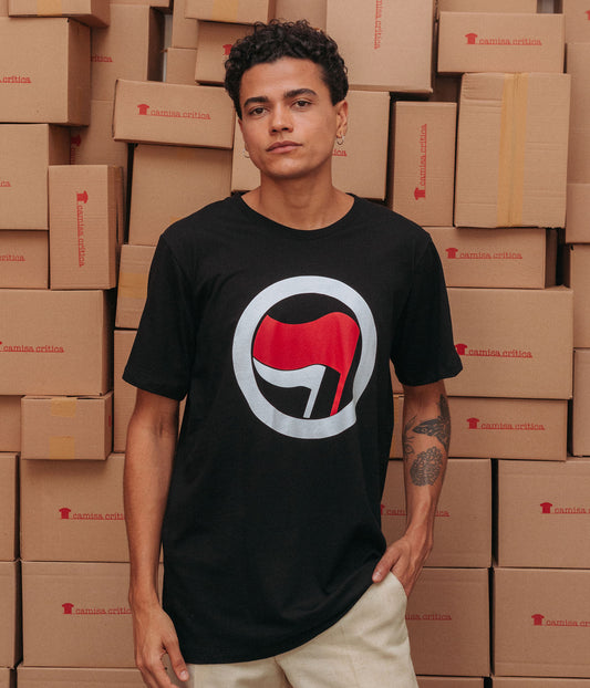 Homem com CAMISETA BÁSICA Símbolo pequeno na altura do peito à direita da Ação Antifascista. Uma bandeira menor e outra maior envoltas por um círculo. 