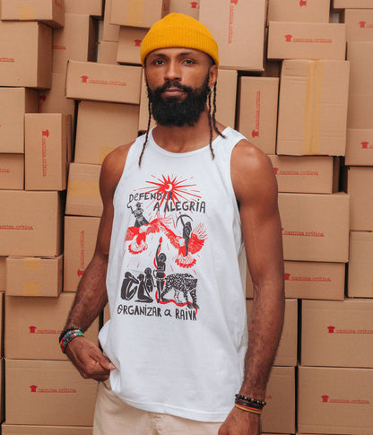 Homem vestindo Camiseta Regata. Estampa: Mulheres harmonizam com animais sobre o mote “defender a alegria” em cima e “organizar a raiva” embaixo. As mulheres representam povos originários, suas ferramentas e relação com o meio ambiente. Quatro mulheres, uma cobra e uma onça embaixo, acima duas mulheres encima de pássaros. Todos olham pra um sol/lua que irradia luz.