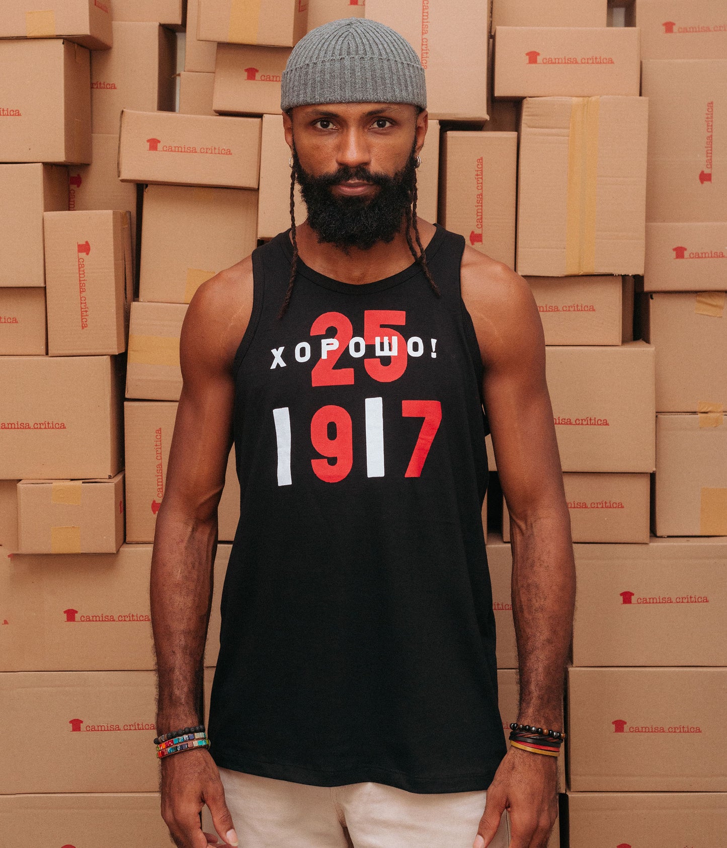 Homem vestindo Camiseta Regata. Estampa: Texto em caracter grande 25(dia da reolução de outubro) e 1917(ano da revolução russa). E em russo está sobre posto ao 25 o texto: BOM!