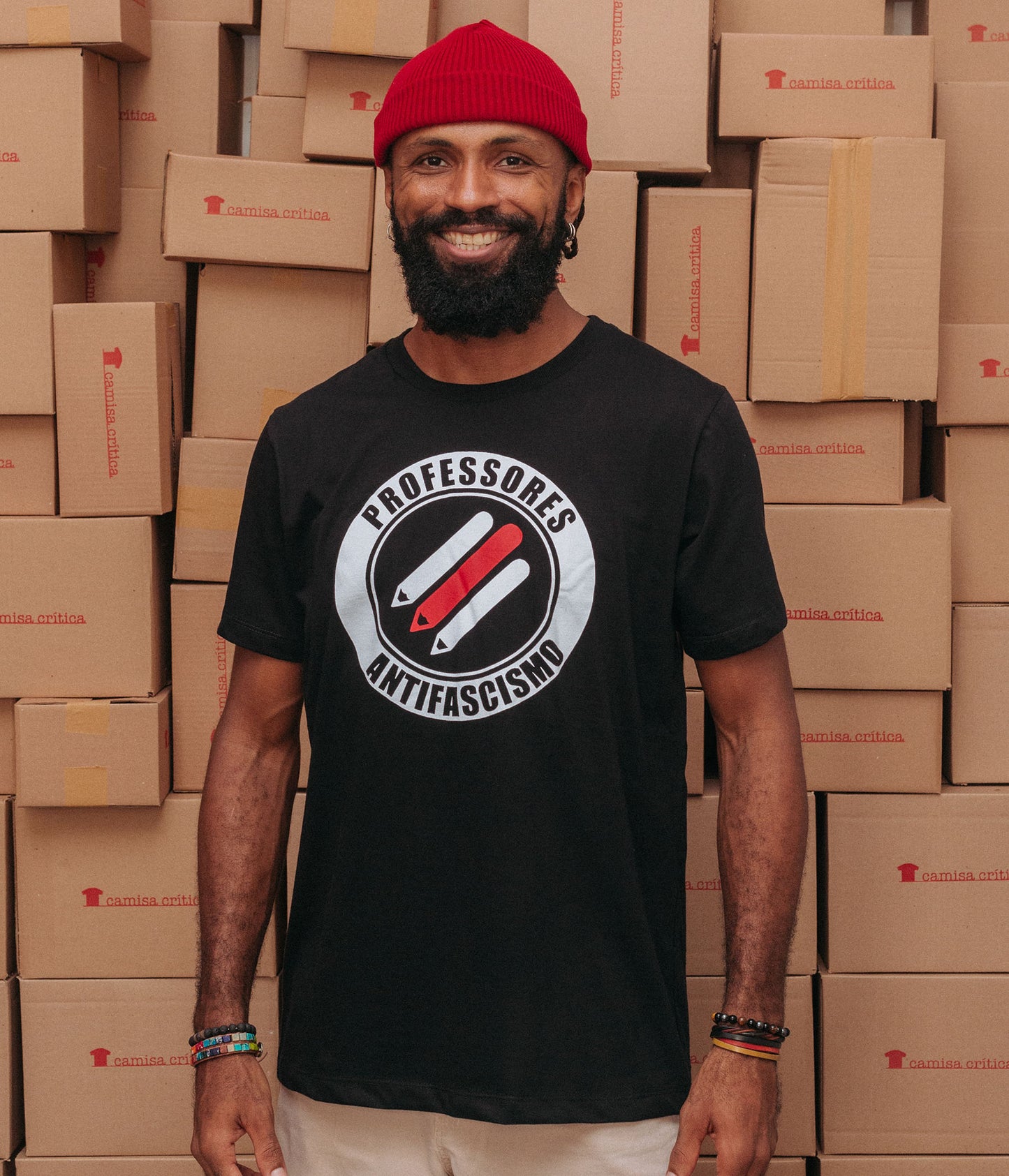 Homem vestindo Camiseta Básica Estampa: Três lápis paralelos na diagonal. Ao redor um círculos onde está escrito Professores Antifascismo.