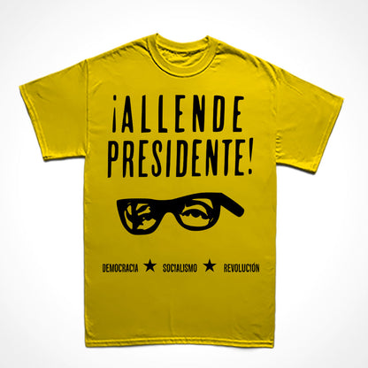 Camiseta Básica Estampa: Texto Allende Presidente com acentos hispânicos, recorte dos olhos e óculos de Salvador Allende, texto no rodapé: DEMOCRACIA, SOCIALISMO e REVOLUCIÓN intercalados por duas estrelas.